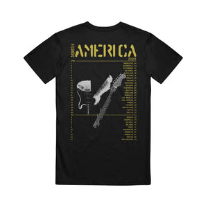 image of the back of a black tee shirt on a white background. the tee has in yellow at the top 2022 america with the list of tour dates and locations below and a broken guitar in the center.